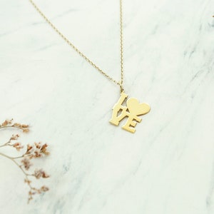 以下が含まれることがあります： ハート型の「O」で「LOVE」と書かれたペンダントが付いたゴールドネックレス。