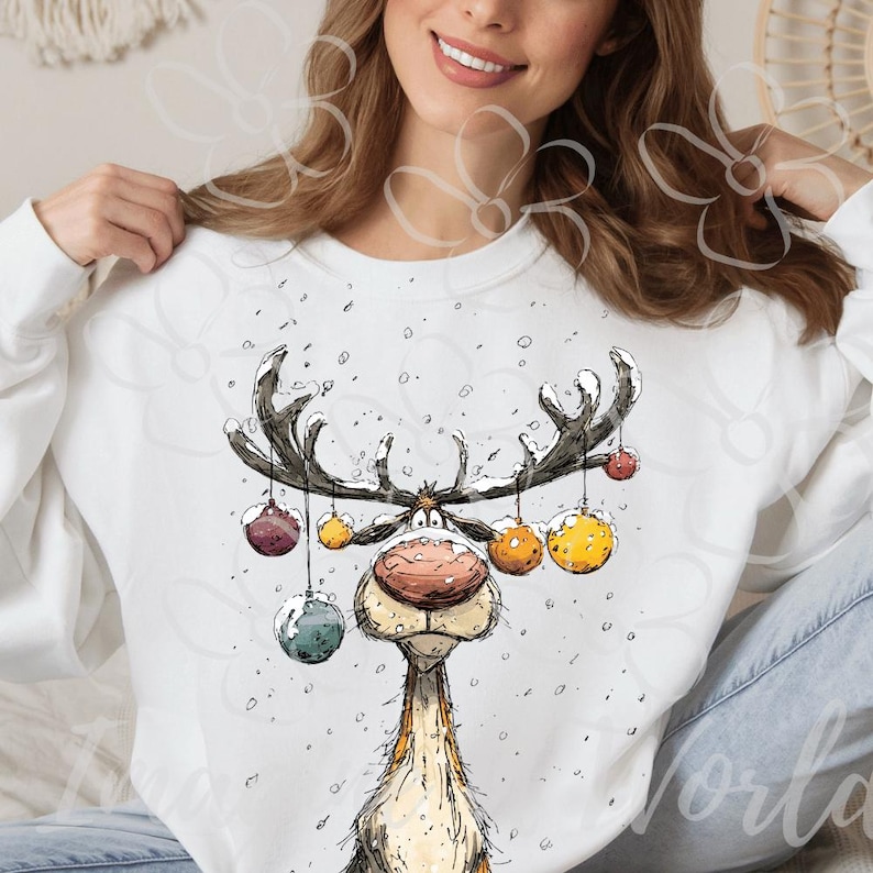 Puede incluir: Sudadera blanca con un dise&ntilde;o caprichoso de reno. El reno tiene grandes cuernos adornados con adornos coloridos. La ilustraci&oacute;n es de estilo caricaturesco, perfecta para la temporada navide&ntilde;a.