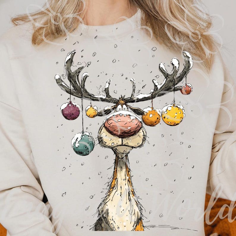 Puede incluir: Una sudadera de color crema con una ilustraci&oacute;n caprichosa de un reno con grandes astas adornadas con coloridas bolas de Navidad. El reno tiene una gran nariz rosada y est&aacute; sobre un fondo nevado, evocando un tema festivo navide&ntilde;o.