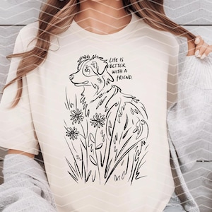 May include: A white t-shirt with a black line drawing of an Australian Shepherd dog standing in a field of flowers. The text "Life is better with a friend." is printed on the shirt.