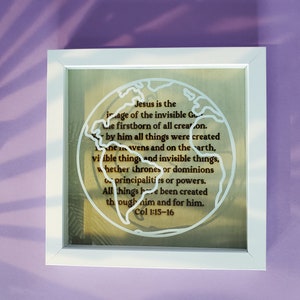 May include: A white framed picture with a beige background and a white outline of the world. The text inside the outline reads "Jesus is the image of the invisible God, the firstborn of all creation. By him all things were created, in the heavens and on the earth, visible things and invisible things, whether thrones or dominions or principalities or powers. All things have been created through him and for him. Col 1:15-16".