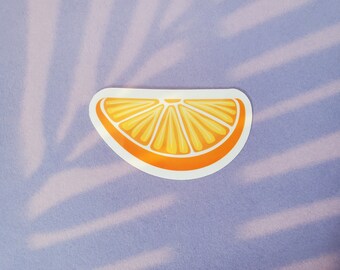 May include: A white sticker with a yellow and orange illustration of a slice of orange.