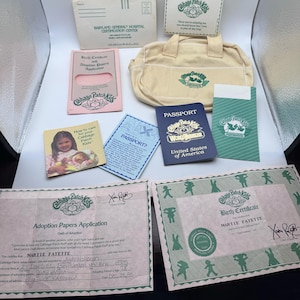 May include: A Cabbage Patch Kids accessory set including a cream-colored fabric bag, a blue United States of America passport, a pink adoption papers application, a birth certificate for Martie Fayette, and various informational cards and envelopes.