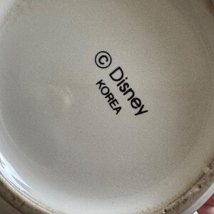 May include: White ceramic mug with a black Disney logo and the text "KOREA" printed on the bottom.