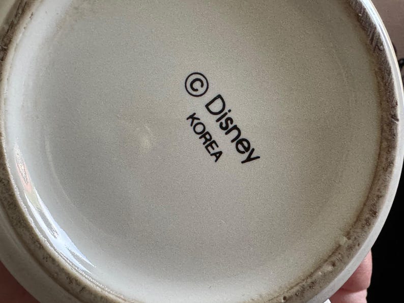 May include: White ceramic mug with a black Disney logo and the text "KOREA" printed on the bottom.