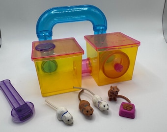May include: A colorful hamster habitat set with a blue handle, two yellow and pink connected enclosures, and miniature toy hamsters and food. Includes a purple accessory.