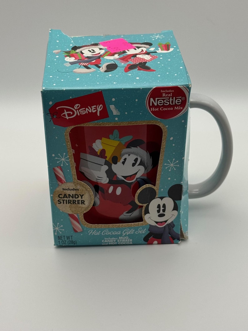 May include: A Disney Hot Cocoa Gift Set featuring Mickey Mouse. The box is teal with snowflake designs and includes a mug, candy stirrer, and Nestle hot cocoa mix. The mug has a grey handle and a Mickey Mouse graphic.
