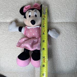 May include: A Minnie Mouse plush toy, approximately 8 inches tall, with a pink polka-dot dress and bow. The toy has black ears, a black nose, and white gloves. The plush is soft and cuddly, perfect for children.