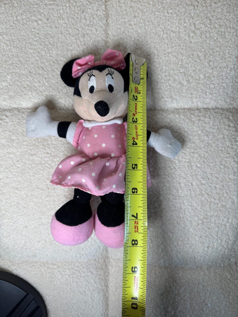 May include: A Minnie Mouse plush toy, approximately 8 inches tall, with a pink polka-dot dress and bow. The toy has black ears, a black nose, and white gloves. The plush is soft and cuddly, perfect for children.