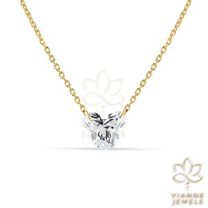 May include: A delicate gold chain necklace featuring a heart-shaped diamond pendant. The diamond is clear and faceted, catching the light. The necklace is a simple, elegant piece of jewelry.