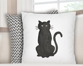 May include: White throw pillow with a black cat silhouette design. The cat is sitting upright with a curved tail and whiskers. A second pillow with a black and white cat pattern is visible.