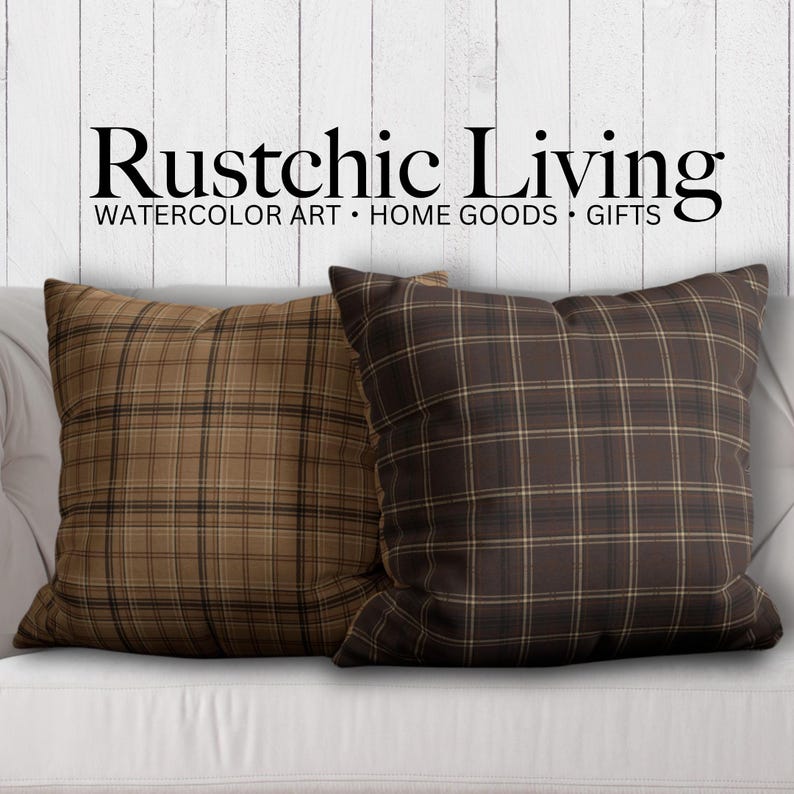 May include: Two brown and tan plaid throw pillows with a white background. The pillows are on a white couch. The text "Rustchic Living Watercolor Art. Home Goods. Gifts" is above the pillows.