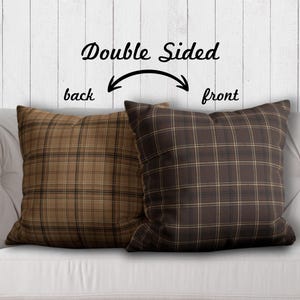 May include: Double-sided throw pillow with a brown and tan plaid pattern. The front side of the pillow has a darker brown plaid, while the back side has a lighter tan plaid.