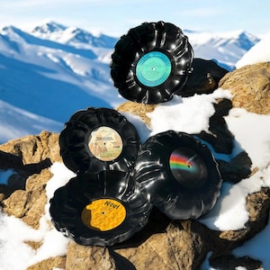 Könnte beinhalten: Vier schwarze Schallplatten-Schalen mit verschiedenen Etiketten auf einem schneebedeckten Berggrund. Die Etiketten beinhalten "Mark McLaughlin", "Ktel" und "The Jackson 5".