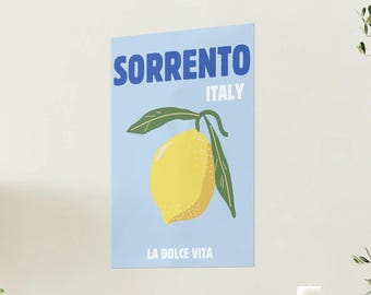 May include: A blue and white poster with the text "SORRENTO ITALY" and "LA DOLCE VITA". A yellow lemon with green leaves is in the center of the poster.
