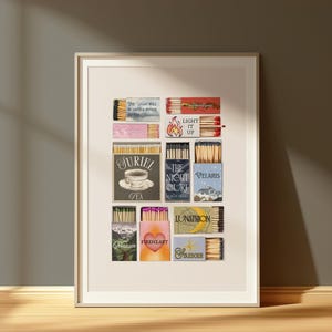 Könnte beinhalten: Ein gerahmter Druck mit verschiedenen Streichholzschachtel-Designs. Die Streichholzschachteln haben unterschiedliche Farben und Texte, darunter "LIGHT IT UP", "JURIEL TEA" und "FIREHEART". Das Kunstwerk wird in einem weißen Rahmen vor einem neutralen Hintergrund präsentiert.