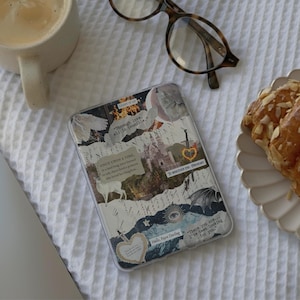 May include: A rectangular e-reader case featuring a collage of fantasy-themed imagery, including a castle, a sword, a deer, and text snippets like "Through love, all is possible" and "Once upon a time" printed on a light-colored background.