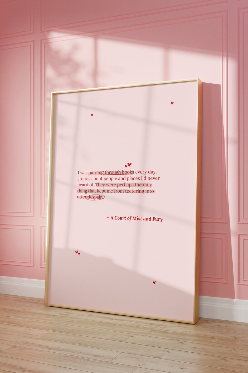 May include: A pink framed poster with a quote from the book "A Court of Mist and Fury" by Sarah J. Maas. The quote reads: "I was burning through books every day, stories about people and places I'd never heard of. They were perhaps the only thing that kept me from teetering into utter despair."