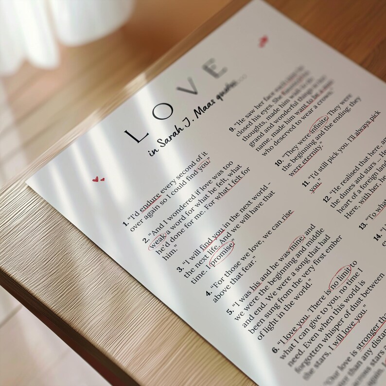 May include: A printed page with the word "LOVE" in large letters, followed by "in Sarah J. Maas quotes." The page features quotes about love, with some words highlighted in red. The paper is on a wooden surface.