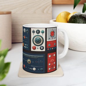 Peut inclure: Une tasse en céramique blanche avec un motif coloré de différents cadrans, boutons et boutons. Le motif est un collage de différents panneaux de commande avec des accents rouges, bleus et blancs.