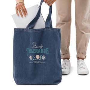 May include: A blue denim tote bag with the text "Barely Tolerable" in a teal and white font. The text is surrounded by a floral design. Below the text is the text "Elizabeth Bennet - Pride and Prejudice".
