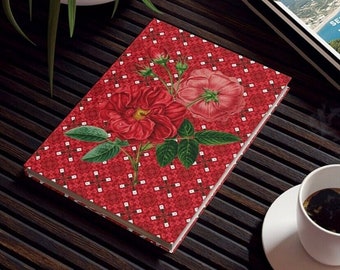 May include: A red journal with a floral design featuring large red roses and green leaves. The cover has a repeating pattern of white diamonds on a red background. The journal is open, revealing blank pages.
