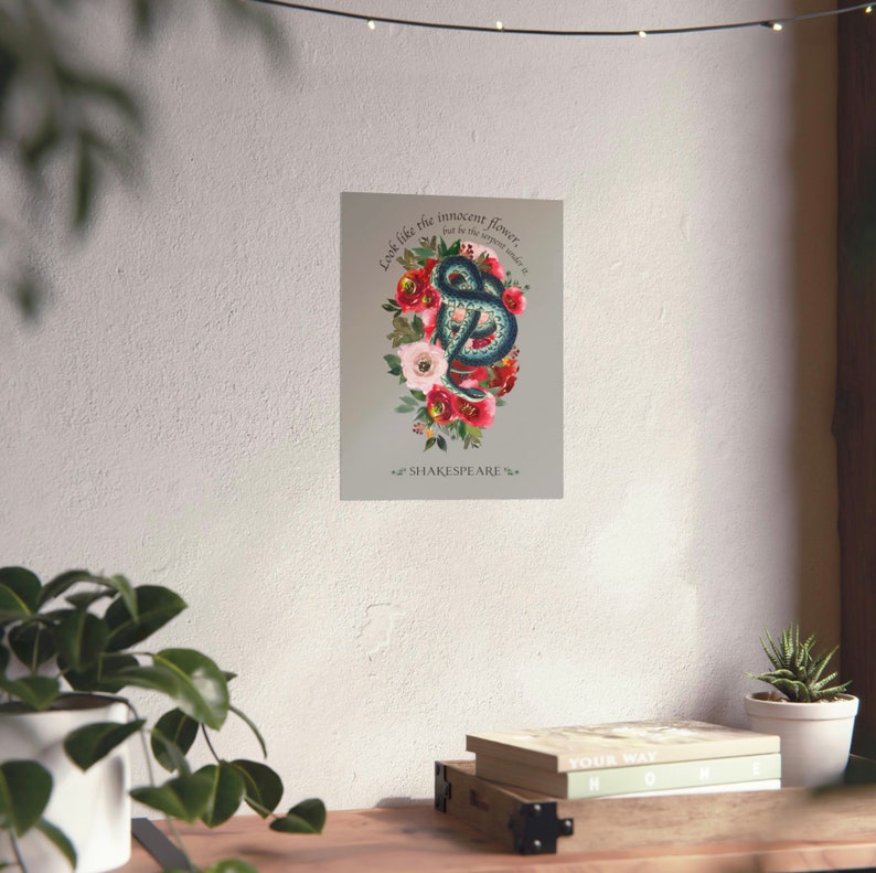 May include: A blue snake coiled around a bouquet of red, pink and white flowers. The quote "Look like the innocent flower, but be the serpent under't" is written above the snake and "SHAKESPEARE" is written below the snake.