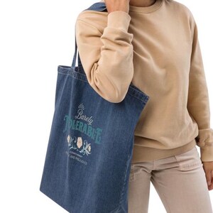 May include: A blue denim tote bag with a white design that says "Barely Tolerable" with a floral design and the text "Classic Story Pride and Prejudice".