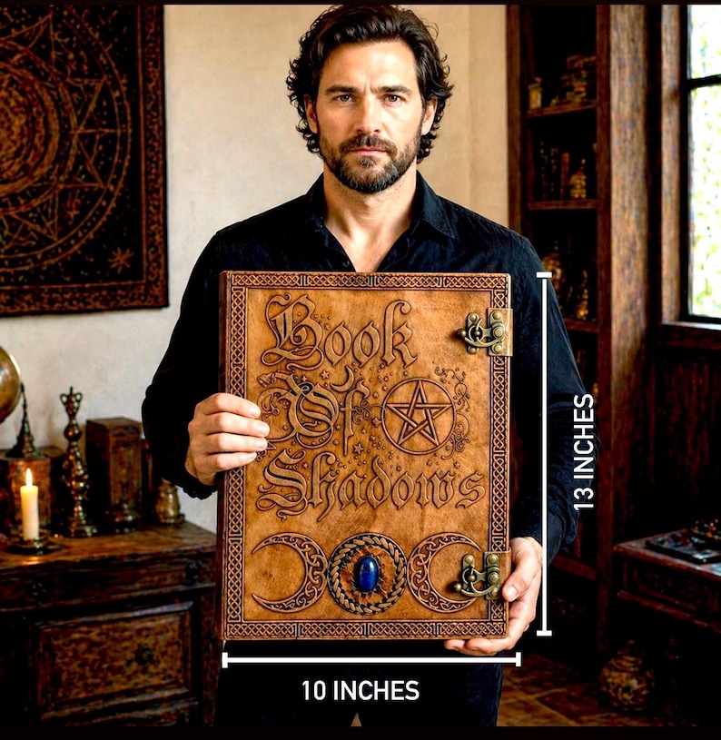 Puede incluir: Un libro encuadernado en cuero marr&oacute;n con el t&iacute;tulo "Book of Shadows" en relieve. El libro presenta un pentagrama, medias lunas y una piedra preciosa azul. Mide 25 cm de ancho y 33 cm de alto.