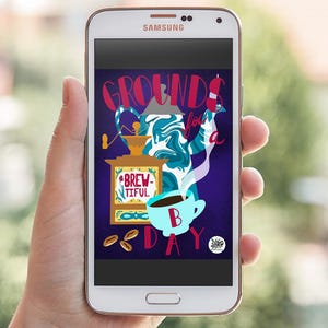 May include: A Samsung smartphone displays a colorful coffee-themed graphic. The artwork features a coffee grinder, a steaming cup, and the words "GROUNDS for a BREW-TIFUL DAY" in a playful font. Coffee beans and a swirl of blue and white complete the design.