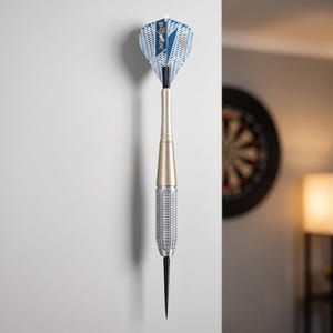 May include: A dart featuring a sharp black point, a textured silver barrel, a smooth gold-toned middle section, and a blue and white flight with the text THE POWER printed on it. The dart is positioned vertically against a plain white surface.