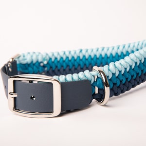 May include: A blue, teal, and light blue braided dog collar with a dark gray leather strap and silver buckle.
