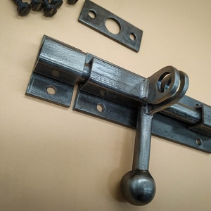 An industrial door latch, handcrafted from steel in a rustic style, ensures the reliable closure of barn doors.