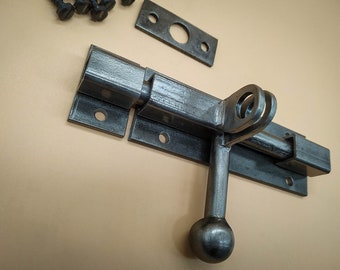 An industrial door latch, handcrafted from steel in a rustic style, ensures the reliable closure of barn doors.