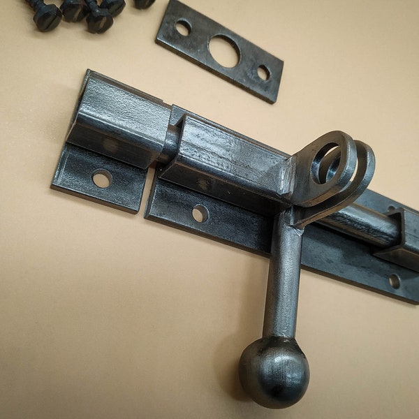 Un loquet de porte industriel fabriqué à la main en acier dans un style rustique, assure une fermeture fiable des portes de grange.