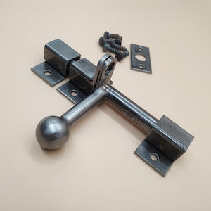 A door latch, handcrafted in a rustic style, ensures reliable and easy closure of doors.