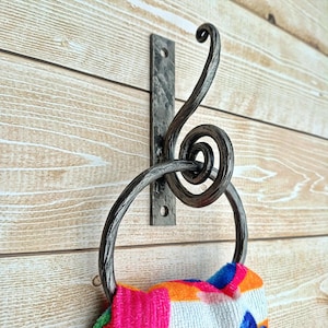 Op de afbeelding: Een witte keramische mok met een zwarte handgreep en de tekst "But First, Coffee" in een vetgedrukte, zwarte letter. De mok staat tegen een vage achtergrond, wat een gezellige setting suggereert.