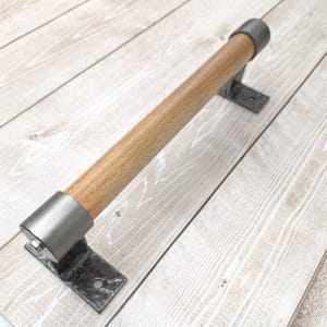 May include: A wooden door handle with a metal end cap and mounting bracket. The handle is made of light wood and the metal is a brushed silver finish.