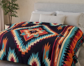 May include: A black, red, orange, and blue patterned throw blanket with a geometric design. The blanket is on a bed with white pillows.