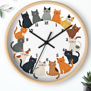 May include: A white clock with a wooden frame features a circle of 12 cats in various poses and colors around the clock face. The clock hands are black and the numbers are black.