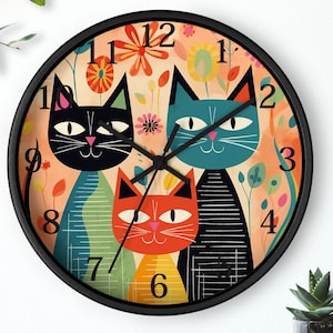 May include: A black and white clock with a colorful design featuring three cats. The cats are stylized and have large eyes. The clock face has a floral design and the numbers 1 through 12 are displayed around the clock face.