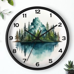 Könnte beinhalten: Eine Wanduhr mit schwarzem Rahmen, weißem Zifferblatt und schwarzen Zahlen. Das Zifferblatt der Uhr zeigt ein Aquarellbild einer Bergkette, die sich in einem See spiegelt. Die Zahlen 12, 1, 2, 3, 4, 5, 6, 7, 8, 9, 10 und 11 sind auf dem Zifferblatt der Uhr sichtbar.