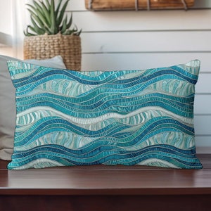 Puede incluir: Una almohada rectangular azul y blanca con un diseño ondulado. La almohada está hecha de tela.