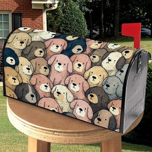 May include: A mailbox with a cover featuring a repeating pattern of cartoon dog faces in various colors, including tan, pink, and brown. The mailbox is silver with a red flag, set on a wooden stand in a yard.