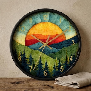 Könnte beinhalten: Eine runde Wanduhr mit schwarzem Rahmen und einer Landschaftsillustration eines Sonnenuntergangs über einem Wald. Das Zifferblatt zeigt goldfarbene Zahlen von 1 bis 12 und dünne goldene Zeiger. Der Hintergrund zeigt geschichtete Hügel und Kiefern.