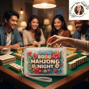 Może przedstawiać: Biała prostokątna torebka na nadgarstek z kolorowym motywem kwiatowym i napisem "MAHJONG NIGHT" pogrubioną czcionką, ozdobiona ilustracjami płytek mahjong. Torebka posiada odpinany biały pasek na nadgarstek oraz złoty metalowy zamek błyskawiczny.