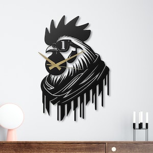 May include: A black metal wall clock shaped like a rooster wearing sunglasses. The clock has gold-colored hands and is mounted on a white wall above a wooden cabinet.