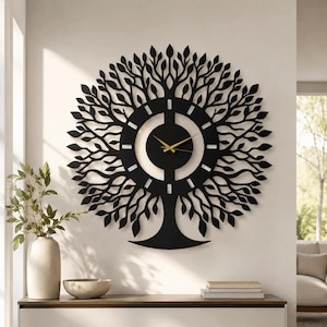 May include: A large, circular wall clock featuring a black, laser-cut metal design of a tree with intricate branches and leaves radiating outward. The central clock face has a solid black center with thin, gold-colored hour and minute hands.