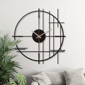 Pode incluir: Relógio de parede geométrico preto e dourado com moldura circular e mostrador preto. O relógio tem um design moderno com linhas finas e uma estética minimalista.