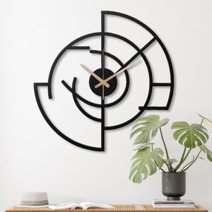 May include: Black and gold geometric wall clock with a modern design. The clock has a circular shape with a black metal frame and gold hands.